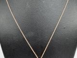 a gold necklace with a pink flower pendant on a mannequin