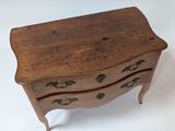 a small wooden chest of drawers on a white surface