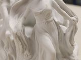 a white statue of two women holding hands on a table