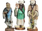 trois figurines représentant des hommes asiatiques debout les uns à côté des autres