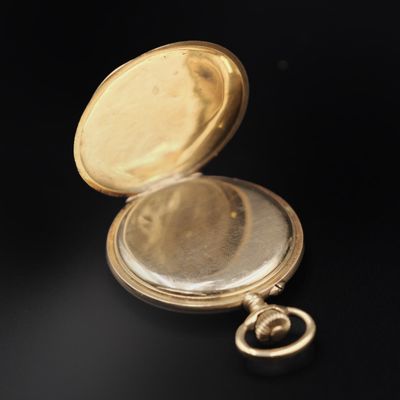 a close up of a gold pocket watch on a black surface