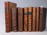 several old books are lined up in a row on a white surface
