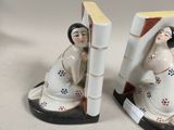 two figurines of a woman reading a book