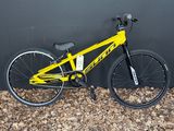 un vélo jaune garé contre un mur, posé à même le sol