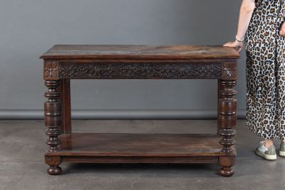 Une personne se tient à côté d'une table, vêtue d'une robe à imprimé léopard.
