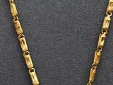 a close up of a gold necklace with a cross on it