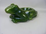une figurine de grenouille verte posée sur une surface blanche