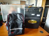 un sac à dos noir et une trousse à outils noire et jaune posés sur une table