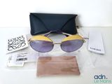 des lunettes de soleil violettes et dorées et un étui noir posés sur une table blanche