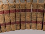 several old books are lined up in a row on a table