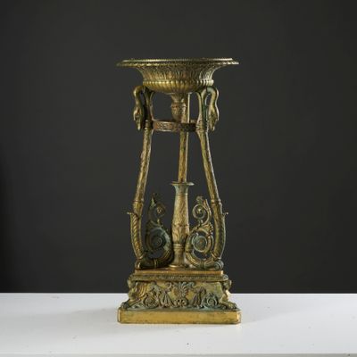 un vase doré posé sur une table blanche, sur fond noir