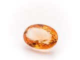 a close up of an orange sapphire stone on a white surface