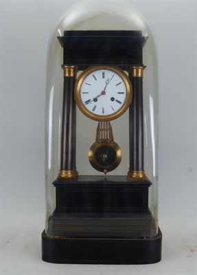 une petite horloge sous un dôme de verre sur une table