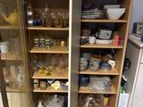 two open shelves in the kitchen with dishes on them