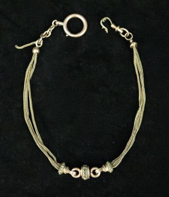 a silver bracelet with two silver beads on a black background