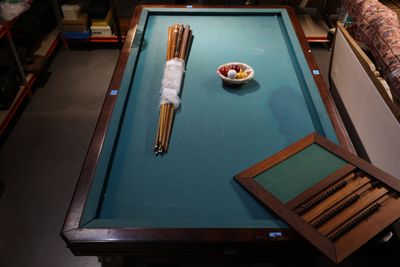 une table de billard sur laquelle sont posés un bol de fruits et deux baguettes