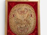 an ornate gold framed picture of a bird and flowers on a red velvet background