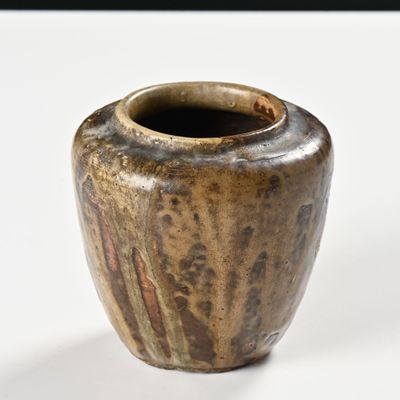 un vase brun posé sur une surface blanche