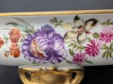 a white vase with a gold handle and a colorful flower design on it