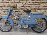 une moto bleue garée près d'un mur de pierre