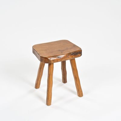 un petit tabouret en bois posé sur une surface blanche