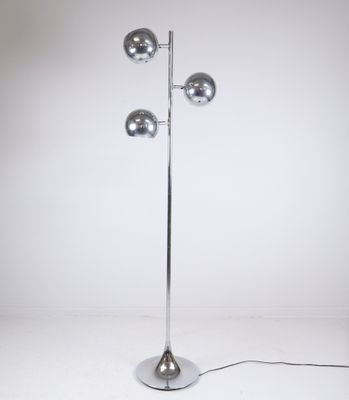 un lampadaire argenté orné de trois boules chromées sur un pied en métal