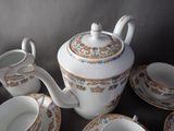 a white tea pot with a gold trim and a tea cup and saucer