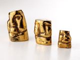 trois figurines en or posées sur une surface blanche