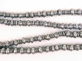 several silver beads are arranged on a white surface