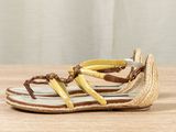 yellow and white sandals on a wooden surface with a curtain in the background