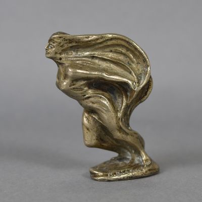 an antique bronze statue of a woman with her hair blowing in the wind