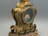 une horloge en or posée sur un socle, surmontée d'un oiseau