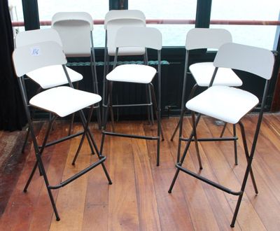 quatre chaises pliantes blanches posées devant une fenêtre, sur un parquet en bois massif