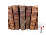 several old books stacked on top of each other on a white surface