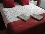 a bed with red pillows and blankets on it in a bedroom