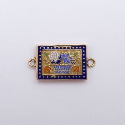 un gros plan d'un pendentif plaqué or et bleu, orné d'un motif floral