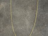 a gold necklace with a yellow pendant on a black background