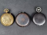 three different types of pocket watches sitting on a black surface