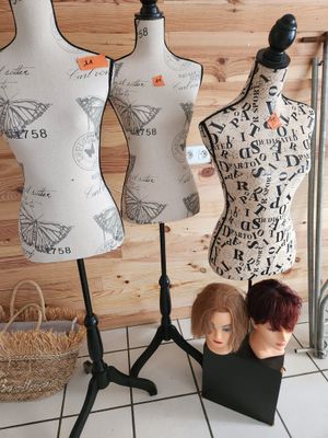 trois mannequins posés sur un socle devant un mur