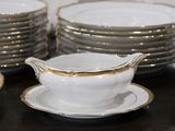a lot of white and gold dishes on a table
