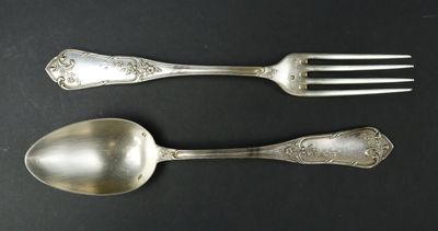 two silver spoons and a fork on a table