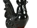 a black and orange rooster figurine on an orange base