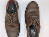 a pair of brown shoes that are on a white surface