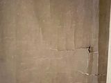 a bathroom with a toilet and a wall with a crack in it