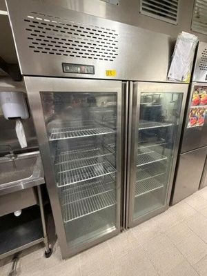 Des réfrigérateurs en acier inoxydable sont alignés dans une cuisine professionnelle