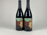 two bottles of red wine sitting next to each other on a table