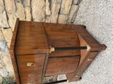 an antique wooden chest with brass hardware on top of a stone wall
