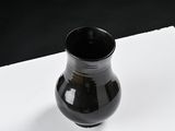 a small black vase sitting on a white surface