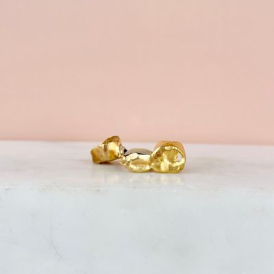 a pair of gold earrings on a marble surface