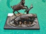une statue en bronze représentant un cerf et une chèvre, posée sur une table